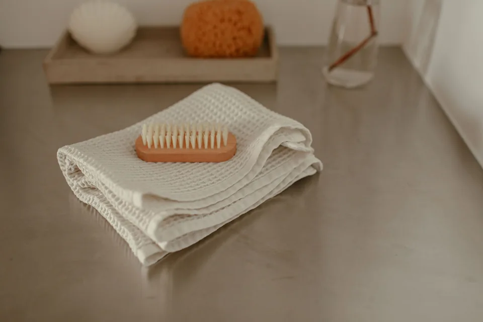 A wooden brush on folded light fabric on a stone bathroom surface.